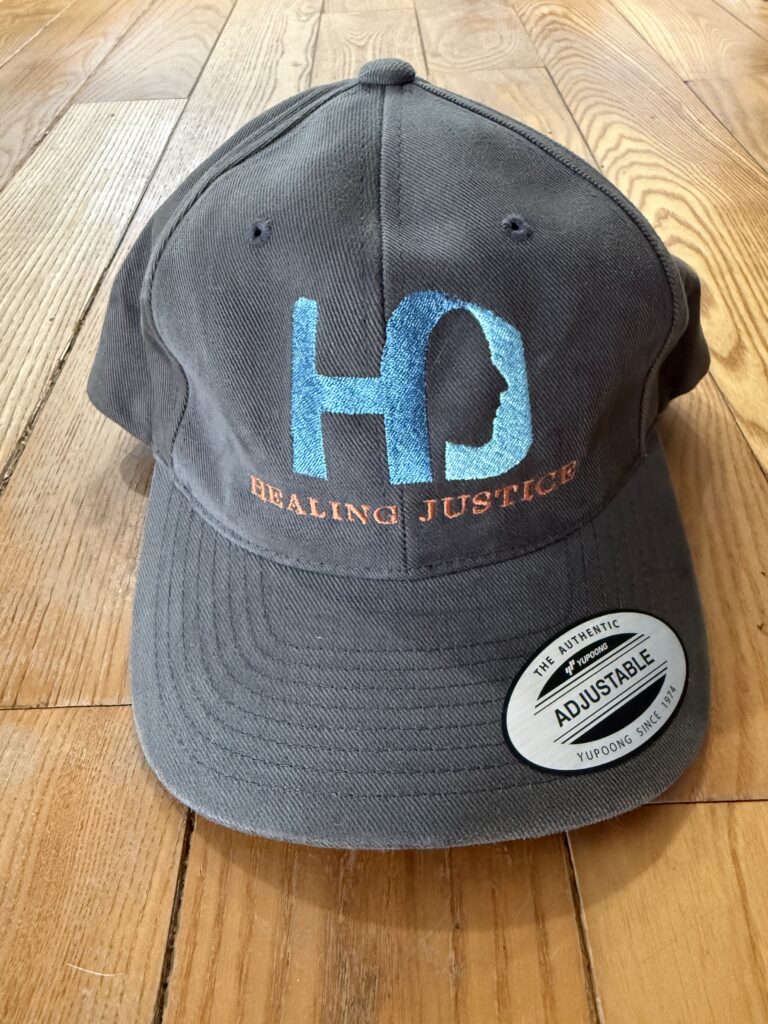 Grey baseball style hat with Healing Justice logo